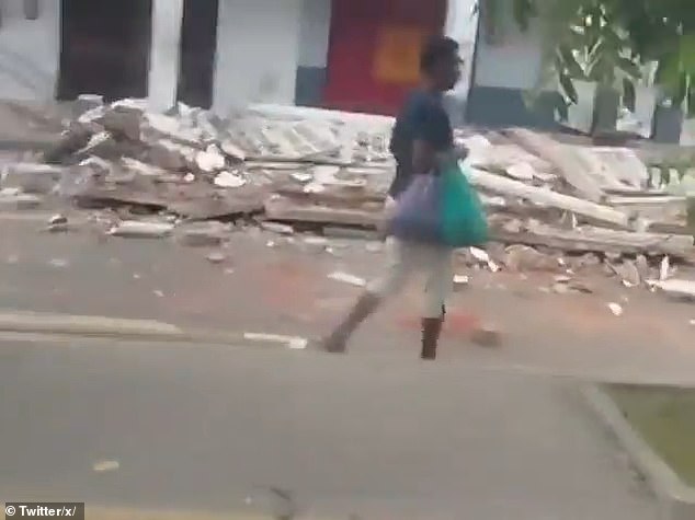 A pedestrian walks past a building that was severely damaged by a 6.3 magnitude earthquake that struck the northwestern Ecuador city of Esmeraldas on Friday at 6:44 am