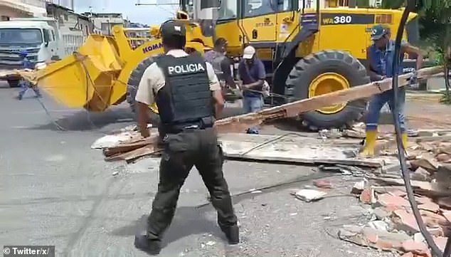 A police officer and construction worker remove debris from a street in Esmeraldas, Ecuador on Friday after an early morning magnitude 6.3 earthquake