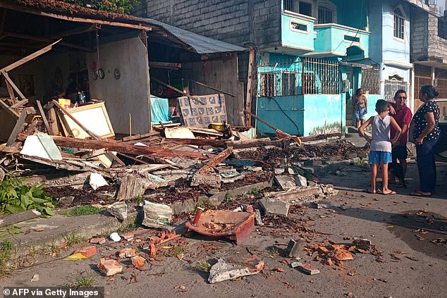 A family stands in front a damaged home after Friday morning's magnitude 6.3 earthquake in Esmeraldas, Ecuador