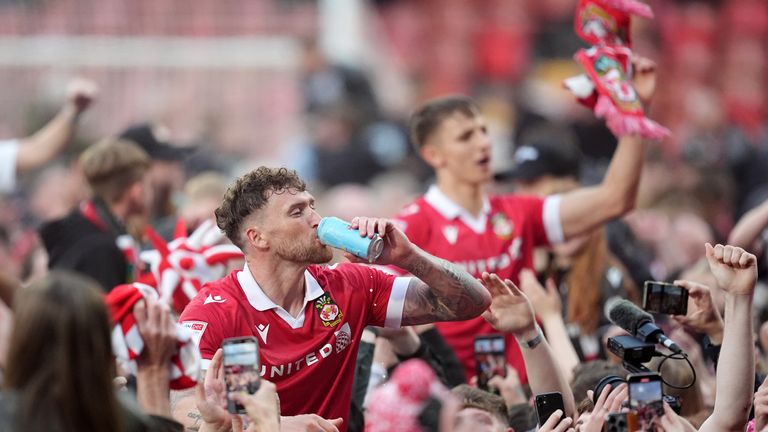 Wrexham's Dan Scarr celebrates with the fans on the pitch after Wrexham won promotion to the Sky Bet Championship after the Sky Bet League One match at SToK Racecourse, Wrexham. Picture date: Saturday April 26, 2025. PA Photo. See PA story SOCCER Wrexham. Photo credit should read: Martin Rickett/PA Wire...RESTRICTIONS: EDITORIAL USE ONLY No use with unauthorised audio, video, data, fixture lists, club/league logos or "live" services. Online in-match use limited to 120 images, no video emulation. No use in betting, games or single club/league/player publications.