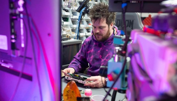 Luke Malpass, the owner and founder of RetroSix, works to repair a Sega Game Gear handheld video game console in their workshop in Stoke-on-Trent, England, on April 1, 2025. —AFP