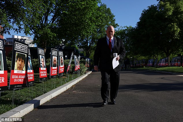 President Donald Trump's "border czar" Tom Homan walks next to signs of people described as arrested illegal immigrants,