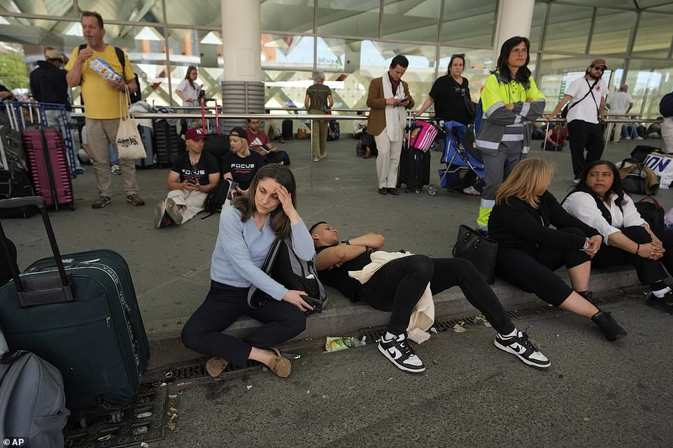 Passengers wait outside Atocha train station during a nationwide power outage