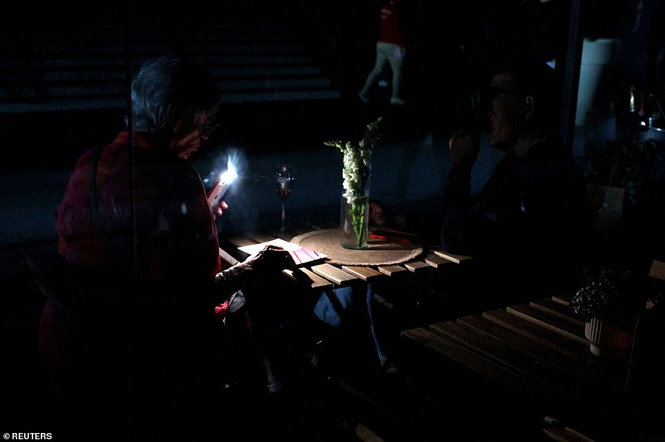 A woman uses her cell phone's flashlight in the dark after Madrid Open matches are suspended due to a power outage