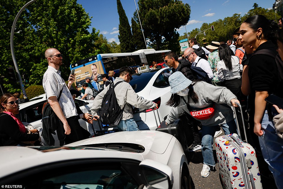 People walk between cars with their luggage during a power outage in Madrid