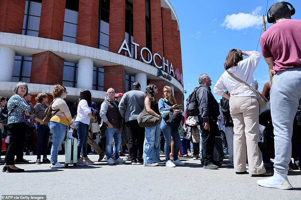 People stand outside the Atocha train station in Madrid after its closure as a massive power outage hits Spain