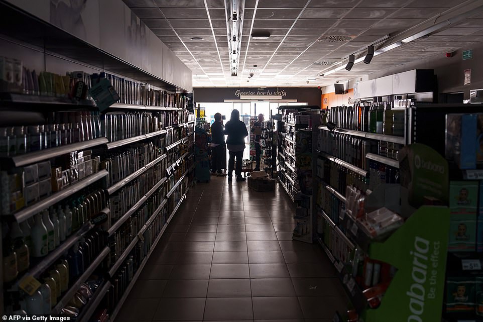 Employees stand in a shop in Burgos, Spain, amid a massive power outage in the country