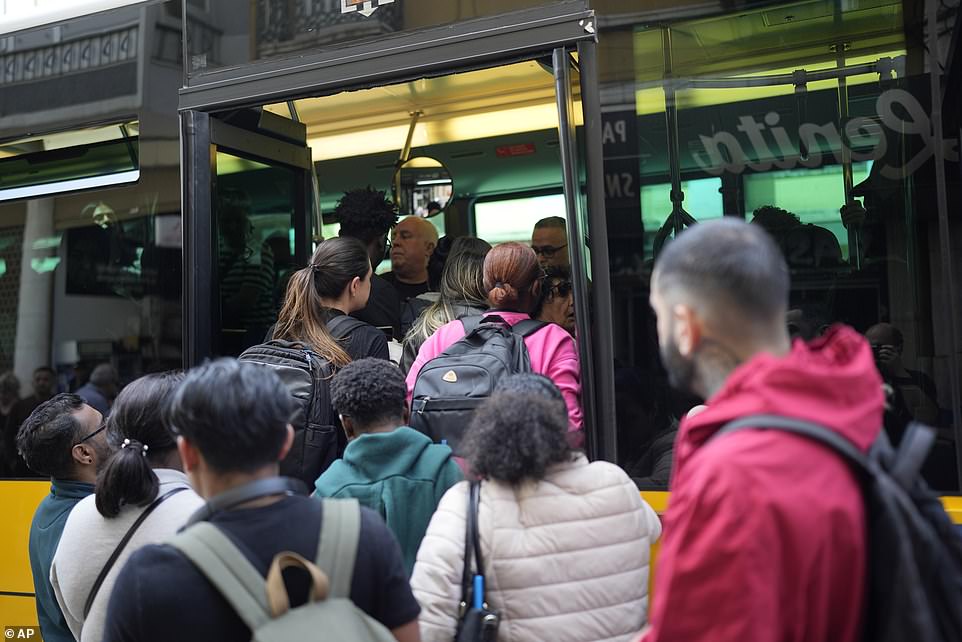 People try to board a crowded bus after the subway stopped running following a power outage in Lisbon