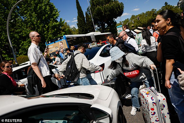 People walk between cars with their luggage during a power outage in Madrid