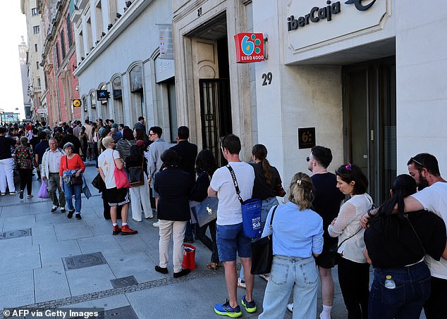 People queue to try to withdraw cash money at an ATM as credit card payment is unavailable due to a massive power outage in Spain, in Madrid on April 28, 2025