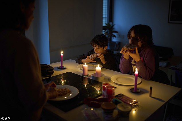 A family eats a snack by candlelight during a blackout in Barcelona, Spain, Monday, April 28, 2025