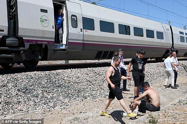 Passengers stand next to a stopped RENFE high-speed AVE train near Cordoba on April 28, 2025, during a massive power cut