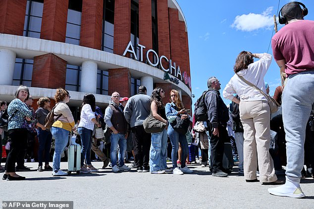 People stand outside the Atocha train station in Madrid after its closure as a massive power outage hits Spain