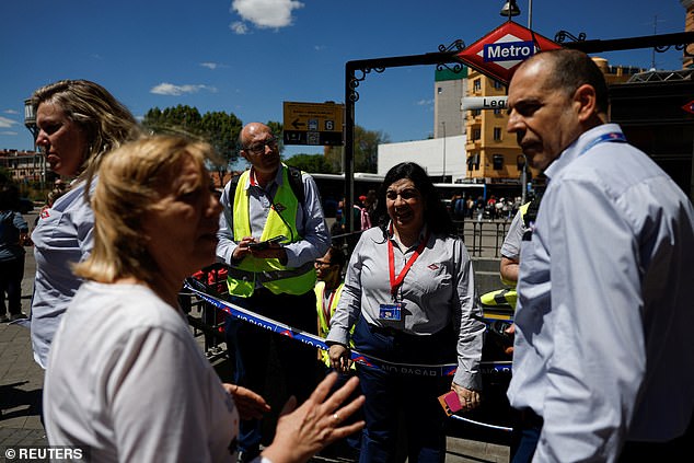 Metro workers explain to a woman that the metro is closed due to a power outage, in Madrid