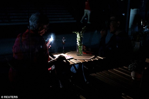 A woman uses her cell phone's flashlight in the dark after Madrid Open matches are suspended due to a power outage