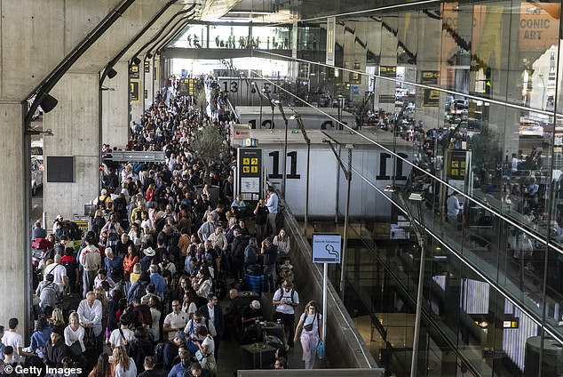 Spain's green energy revolution was under scrutiny yesterday for making massive power cuts 'much worse' as millions were plunged into blackout chaos. Pictured: Crowds waiting for a taxi at Barajas Airport in Madrid