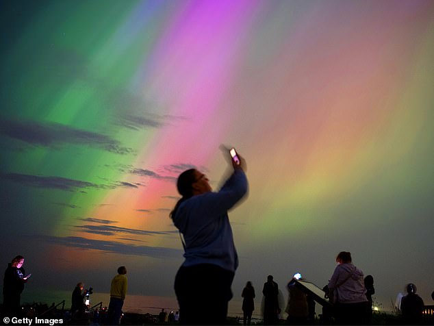 People visit St Mary's lighthouse in Whitley Bay to see the aurora borealis, commonly known as the northern lights, on May 10, 2024 in Whitley Bay