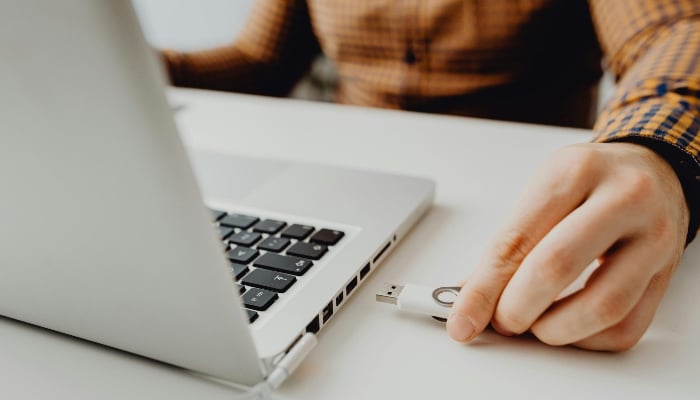 Representative image shows a person plugging a USB drive into a laptop. — Pexels