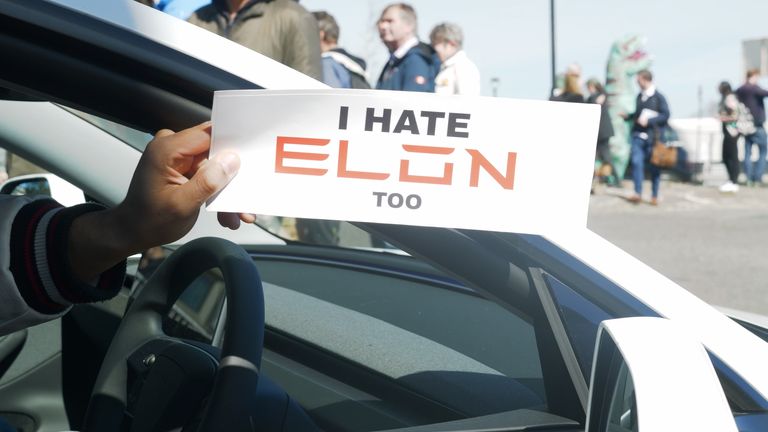 A Tesla owner holds this sign at a dealership in west London.