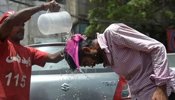 An Edhi volunteer pours water on a pedestrian along a street during a hot summer day in Karachi. — AFP/File
