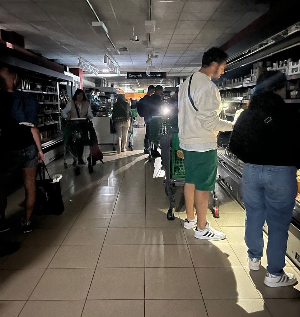 Shoppers at a Spanish supermarket fill their baskets by torchlight amid the blackout