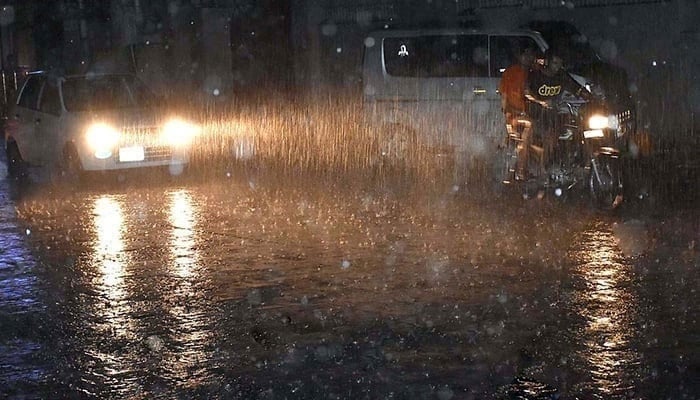 Commuters on their way during heavy rain in Karachi on June 25, 2023. — APP