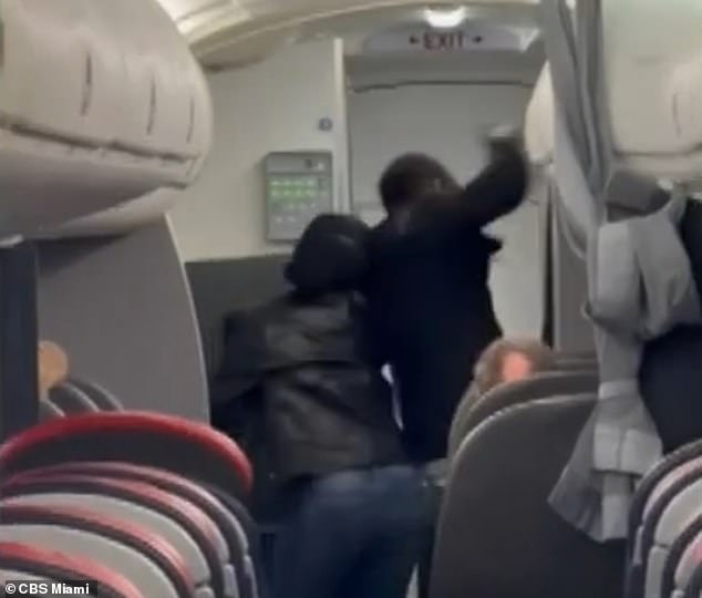 Other passengers had to restrain him after he lashed out a flight attendant, before authorities boarded the flight. He is seen here raising his fist, while holding onto his sister