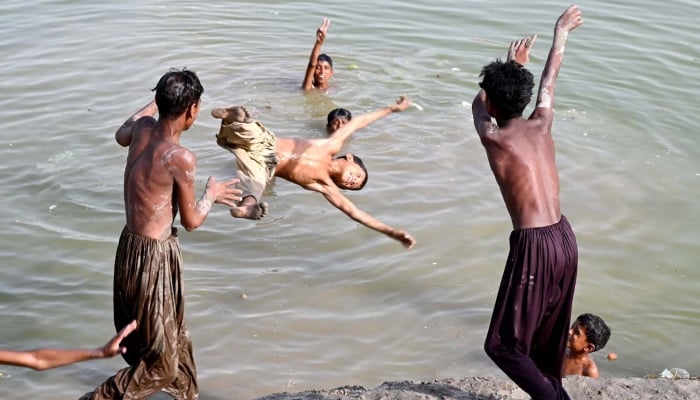 Youngsters jumping and bathing in Rice Canal to get relief from sizzling hot weather in Larkana, April 18, 2025. — APP