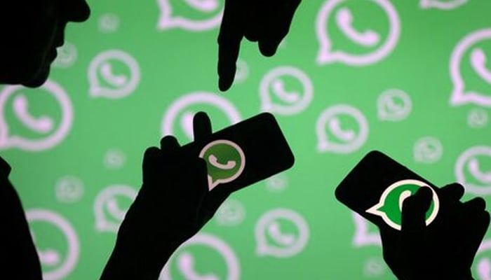 Men pose with smartphones in front of displayed Whatsapp logo in this illustration September 14, 2017. — Reuters
