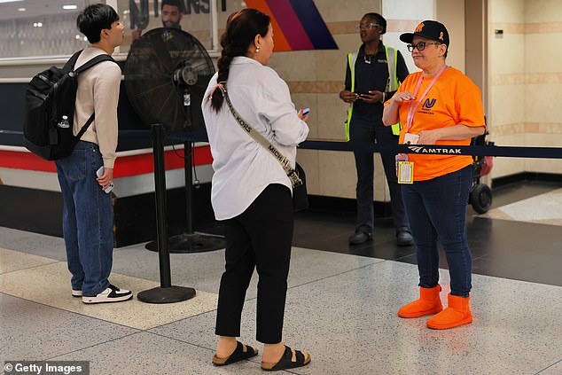 Travelers speak with NJ Transit employees at Penn Station on May 16, 2025 in New York