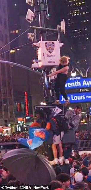 A fan climbs a light pole on Seventh Avenue