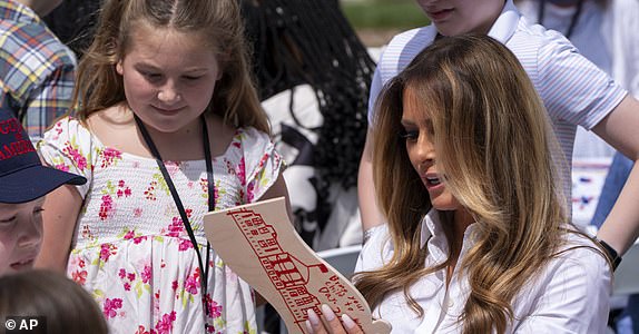 First lady Melania Trump looks at a decorated flag as she participates in flag decorating during a Take Our Child to Work Day event in the Jacqueline Kennedy Garden at the White House, Tuesday, May 20, 2025, in Washington. (AP Photo/Alex Brandon)