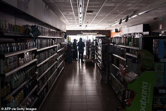 Employees stand inside a supermarket without lights in Burgos, Spain on April 28, 2025, amid a blackout across the Iberian peninsular. Spain said it wasn't ruling out anything as it explored possible causes, as yet undetermined