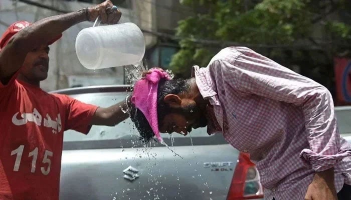An Edhi volunteer pours water on a pedestrian along a street during a hot summer day in Karachi. — AFP/File
