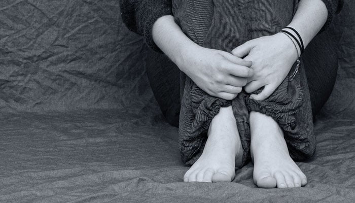 This representational image shows a person sitting with their arms wrapped around their legs. — Pixabay