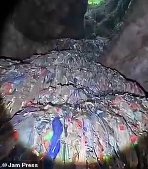 Explorers can be seen staring as they cast a torch around the multicolored rubbish mountains