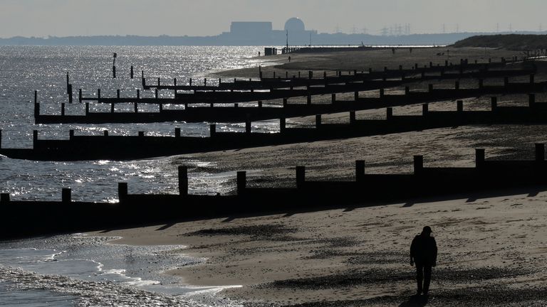 A man walks along the Suffolk coast with the Sizewell B nuclear power station on the horizon
