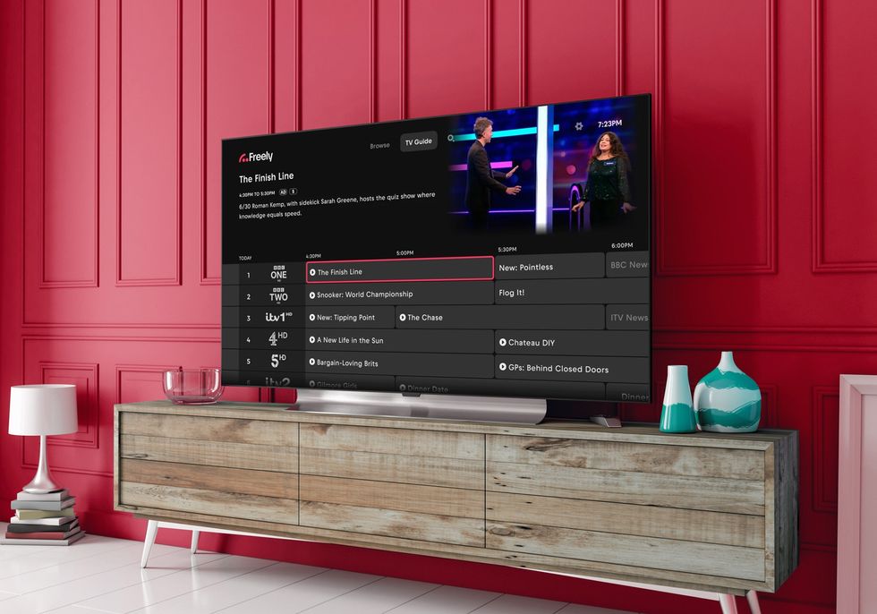 Smart TV in a living room with the Freely logo in the background with the Backwards TV Guide feature shown on-screen