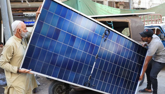 Men load solar panels on a rickshaw (tuk tuk) at a market, in Karachi, March 26, 2025. — Reuters