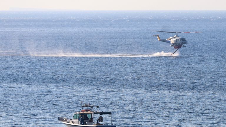 A firefighting helicopter picks up water from the sea, as a wildfire burns near Lerapetra, on the island of Crete, Greece.
Pic: Reuters
