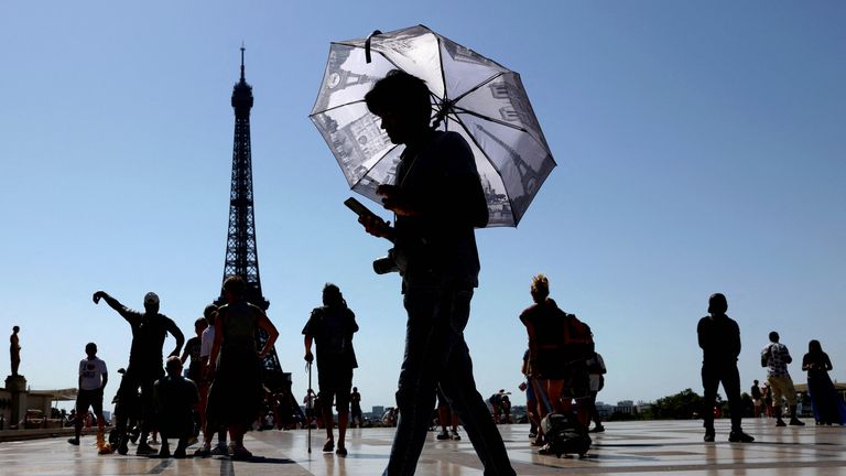 A tourist holding an umbrella to protect himself from the sun walks at Trocadero square next to the Eiffel Tower.
Pic Reuters