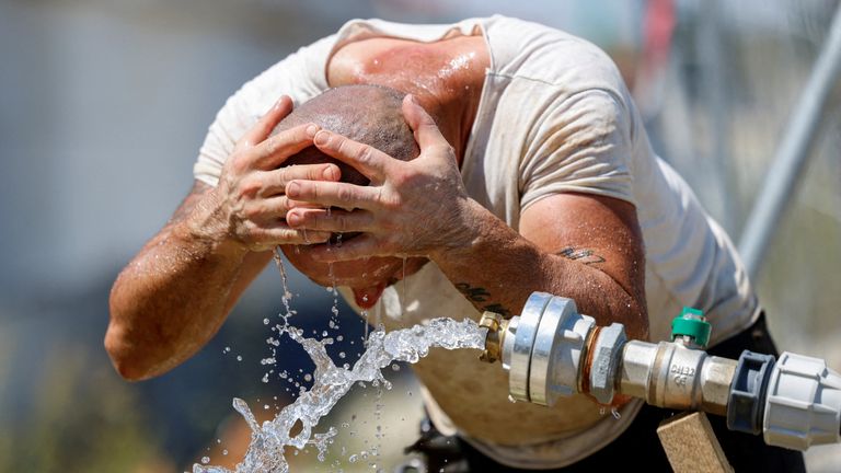 A construction worker freshens up with water at a construction area in Munich, Germany July 1, 2025. REUTERS/Michaela Stache TPX IMAGES OF T