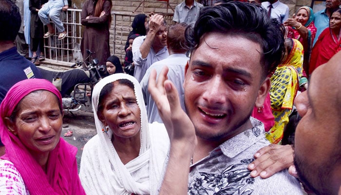Grief-stricken family members break down in tears at the tragic site of a collapsed residential building in Baghdadi, Lyari on July 4, 2025. — APP