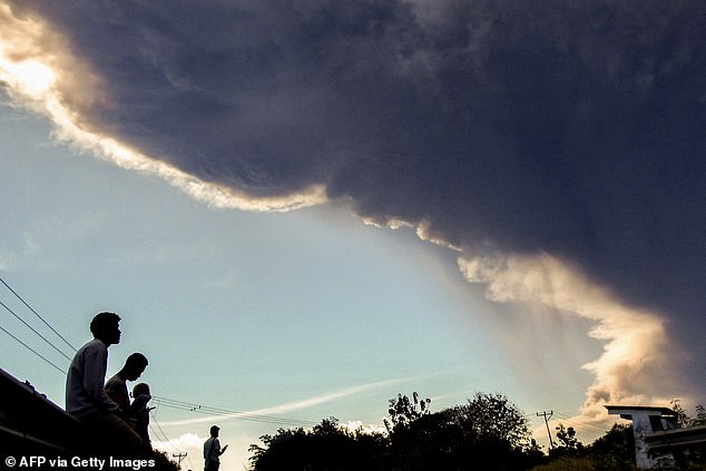 Villagers observe Mount Lewotobi Laki-laki as it erupts, as seen from Nangahale village in Sikka, East Nusa Tenggara on July 7, 2025