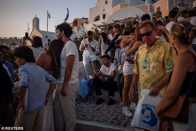 Santorini's mayor Nikos Zorzos stressed last year that there need to be 'limits' to the numbers of tourists descending on the island, warning that they could begin to 'sink under overtourism' (Pictured: tourists viewing Santorini's sunset on July 25, 2024)