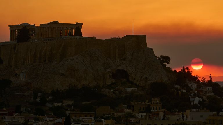The sun sets behind the Acropolis hill as smoke from a nearby wildfire fills the sky during a heatwave in Athens, Greece, Saturday, July 26, 2025. (AP Photo/Petros Giannakouris)