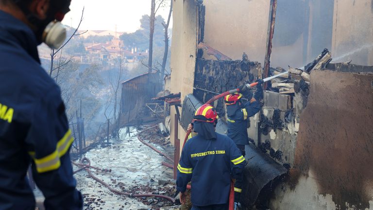 Firefighters try to extinguish a fire at house during a wildfire, in the northwestern suburb of Kryoneri, in Athens, Greece, Saturday, July 26, 2025. (AP Photo/Yorgos Karahalis)