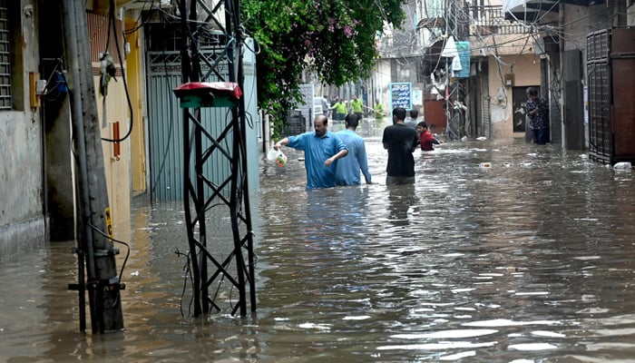 People make their way through the Tipu Road area, submerged in water due to heavy rain experienced in Rawalpindi on July 17, 2025. — APP