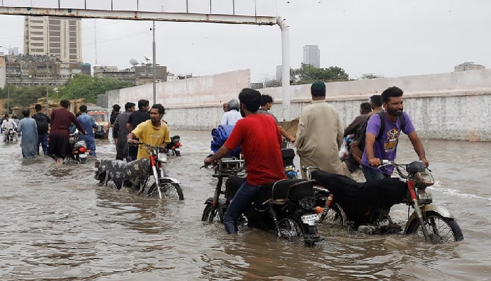 Residents commute through a flooded road during the monsoon season in Karachi, July 9, 2022.— Reuters