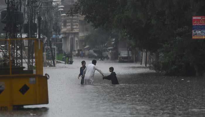 People wade through the flooded street after during the monssoon rain in Rawalpindi on July 17, 2025. — Reuters